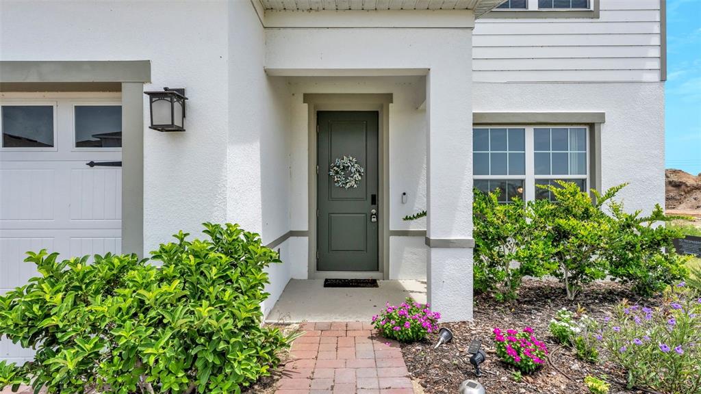 The exterior view shows a white house with a dark green front door and landscaping — 2075 AIREDALE WAY, LAKE ALFRED, FL