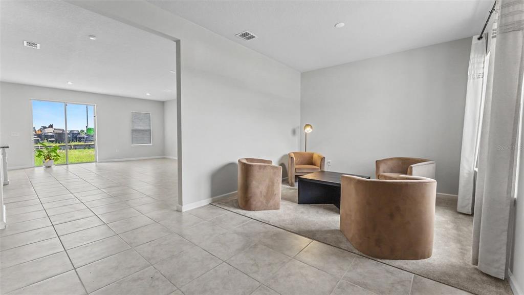 A living area with tile flooring, a carpeted seating nook, and a sliding glass door — 2075 AIREDALE WAY, LAKE ALFRED, FL
