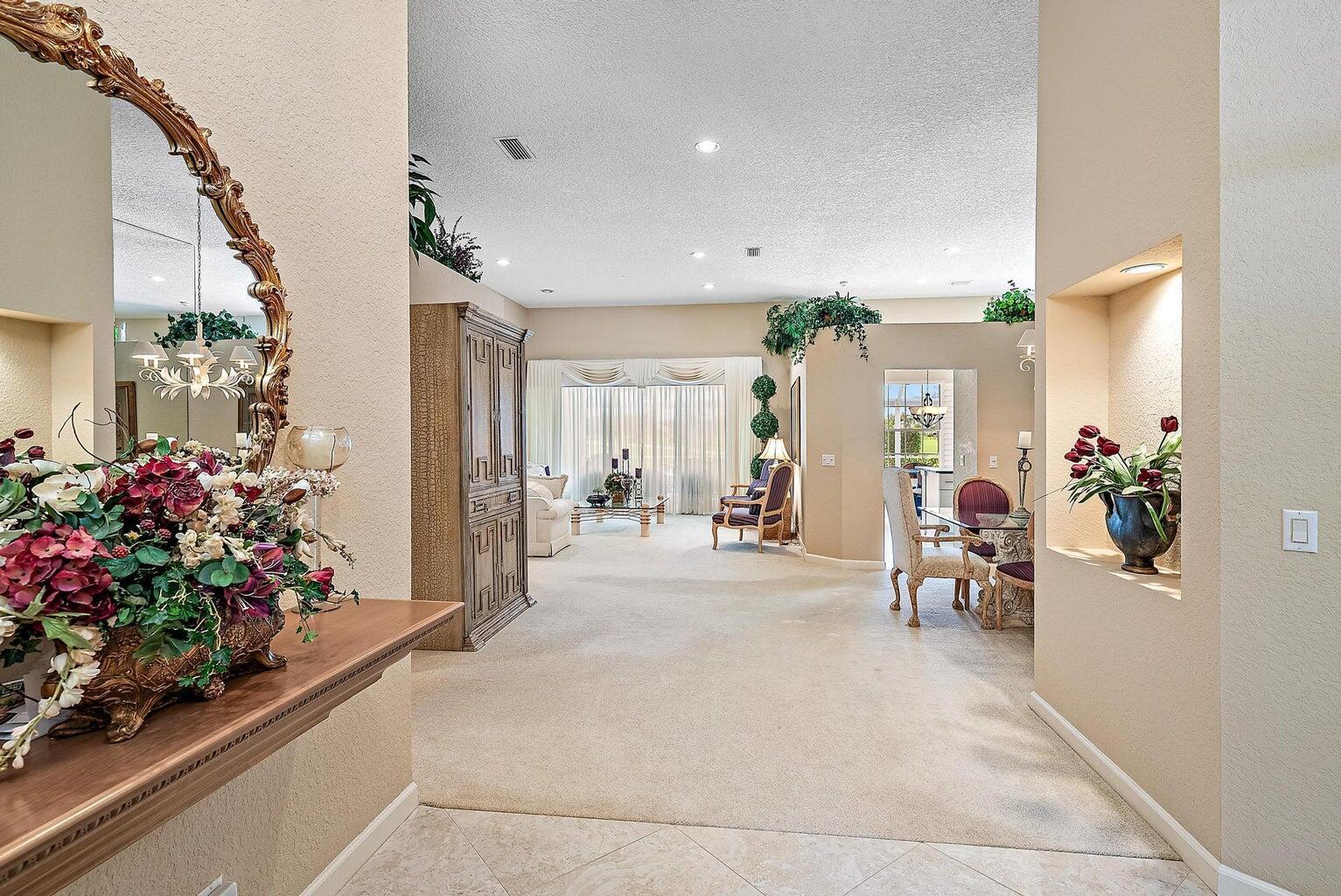 A view from a tiled foyer looking into a carpeted living and dining area — 240 Eagleton Estate Boulevard, Palm Beach Gardens FL 33418, PALM BEACH GARDENS, FL
