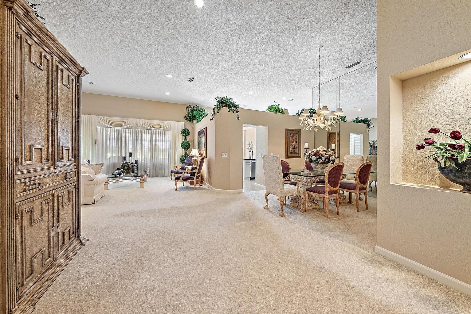 A living and dining area with beige carpet, a glass dining table, and neutral walls — 240 Eagleton Estate Boulevard, Palm Beach Gardens FL 33418, PALM BEACH GARDENS, FL