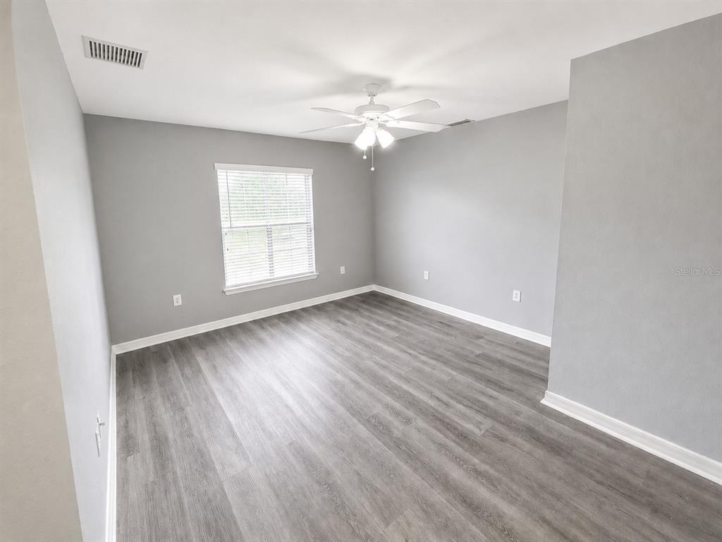 An empty bedroom features gray walls, wood-look flooring, a ceiling fan, and a window — 3011 SHAWNEE TER, NORTH PORT, FL