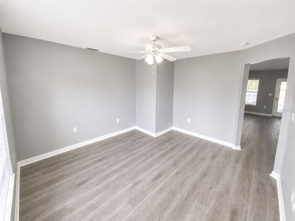 An empty room with gray walls, light wood-look flooring, and a ceiling fan — 3011 SHAWNEE TER, NORTH PORT, FL