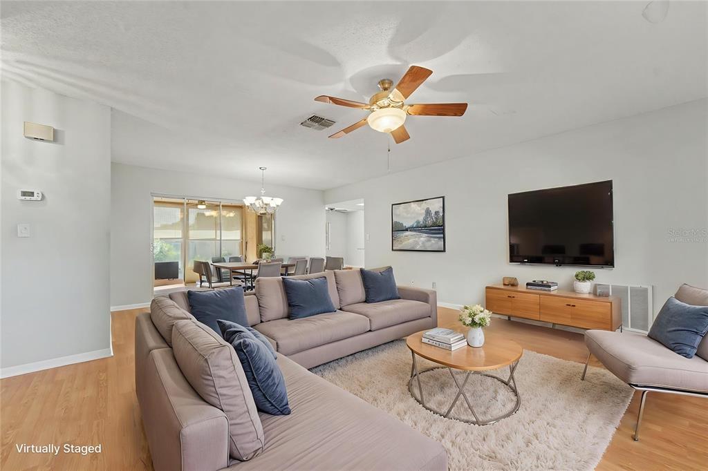 A living room with a sectional sofa, coffee table, television, and wood-look flooring — 8741 ELM LEAF COURT, PORT RICHEY, FL