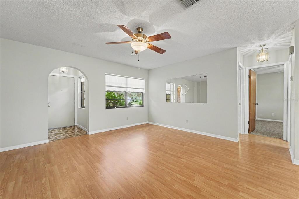 A living room with light wood flooring, a ceiling fan, and an arched entryway — 8741 ELM LEAF COURT, PORT RICHEY, FL