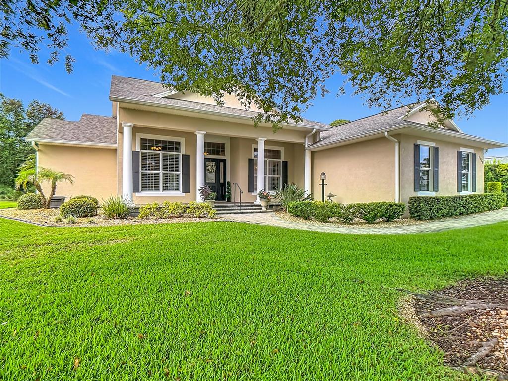 A single-story tan house with a covered entryway, white columns, and a manicured lawn — 5056 MYRTLE BEACH DRIVE, SEBRING, FL