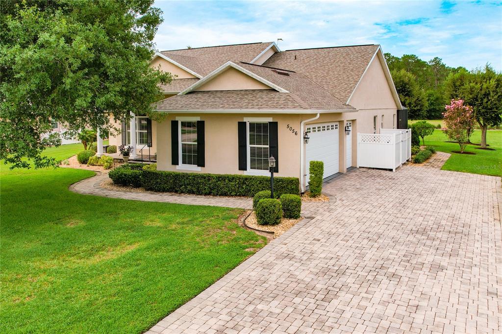 A tan single-story house with a paved driveway, a two-car garage, and a landscaped lawn — 5056 MYRTLE BEACH DRIVE, SEBRING, FL