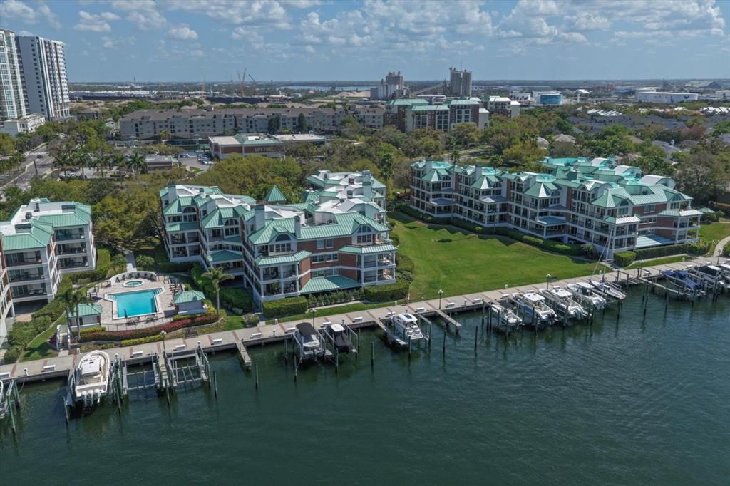 An aerial view shows waterfront condominium buildings with green roofs, a pool, and boat slips — 0 SEDDON COVE WAY UNIT 19, TAMPA, FL