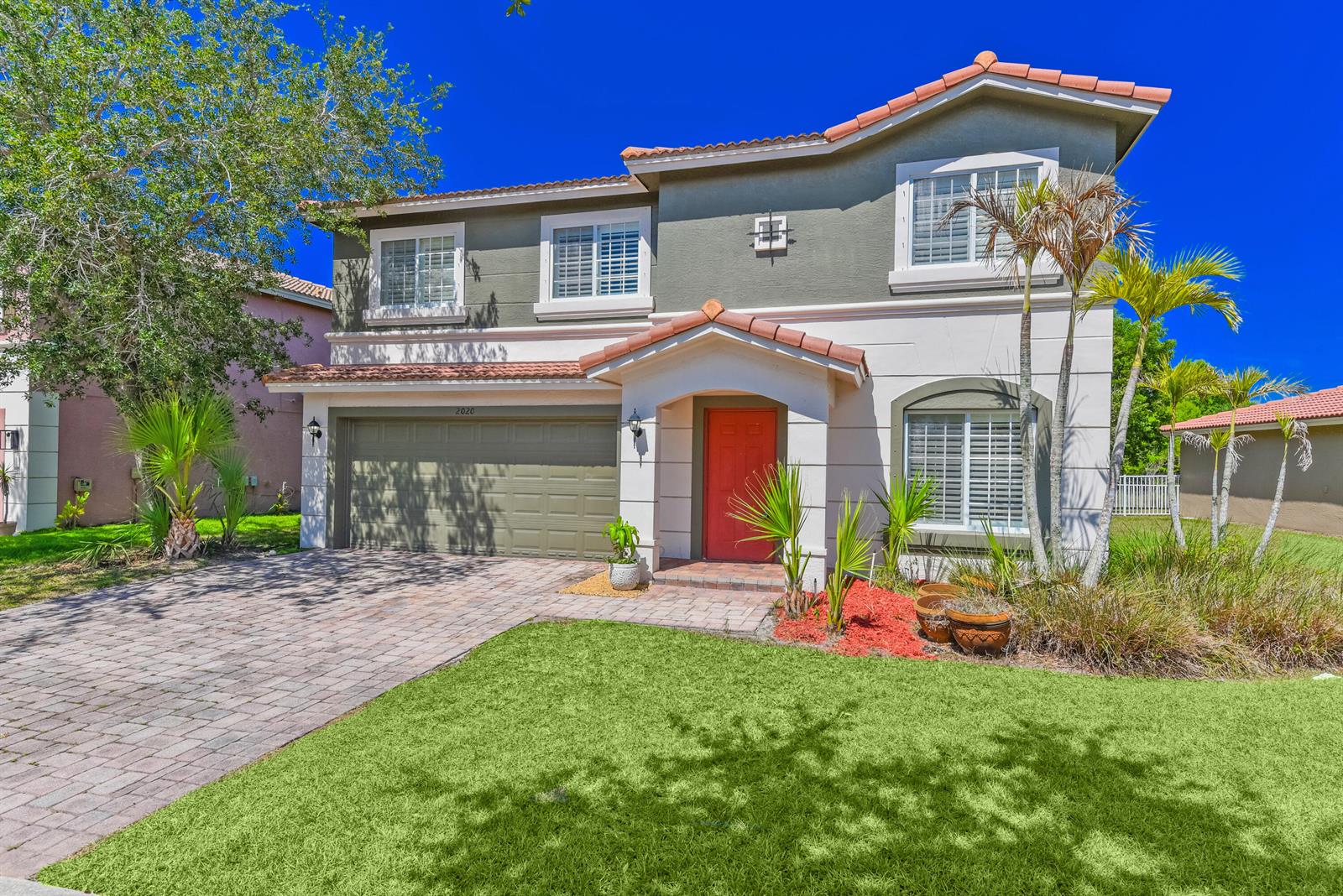 A two-story house with a red front door, tiled roof, and a paved driveway — 2020 SW Newport Isles Boulevard, FL 34953, FL