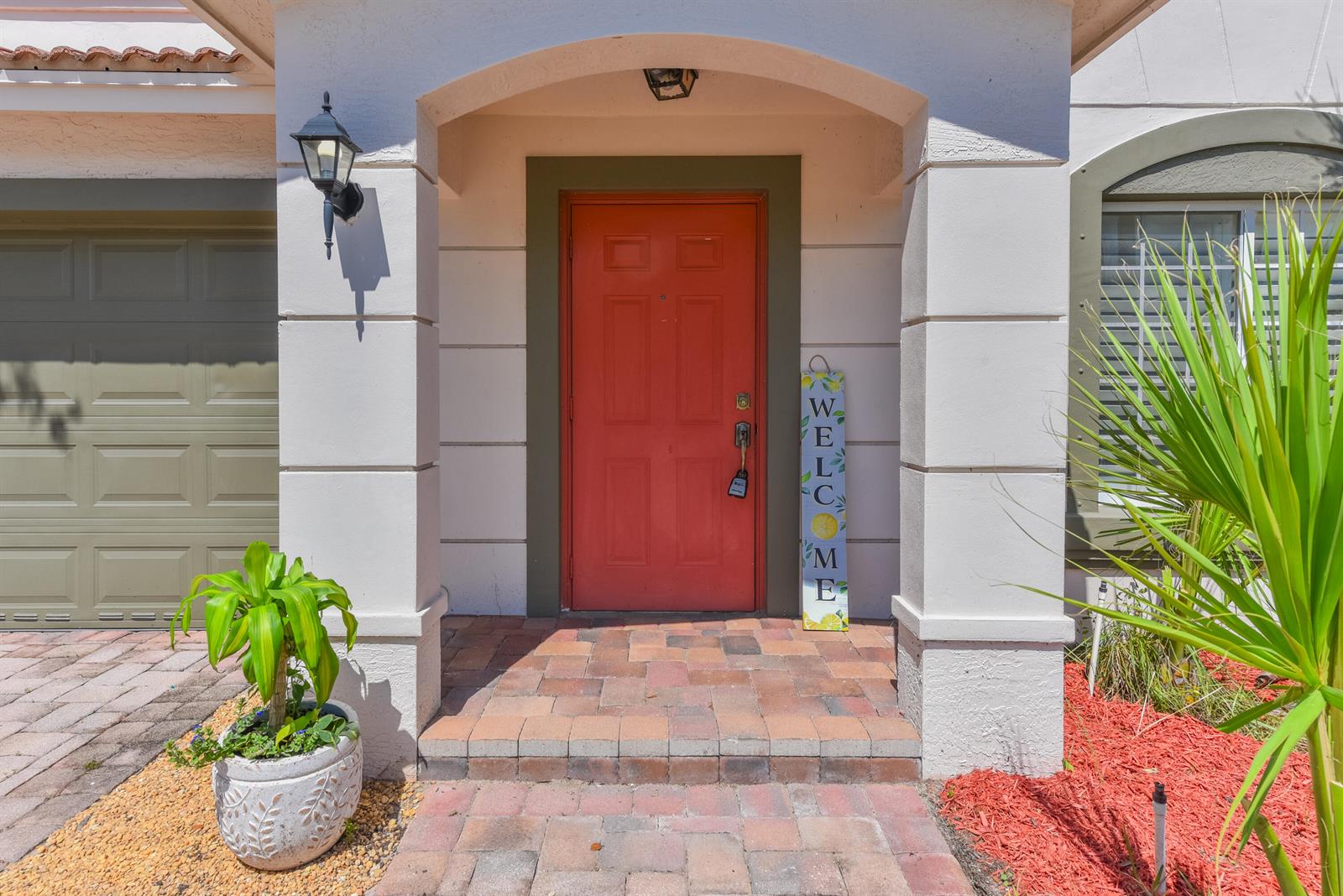 The exterior entrance features a red front door, a welcome sign, and a paved walkway — 2020 SW Newport Isles Boulevard, FL 34953, FL