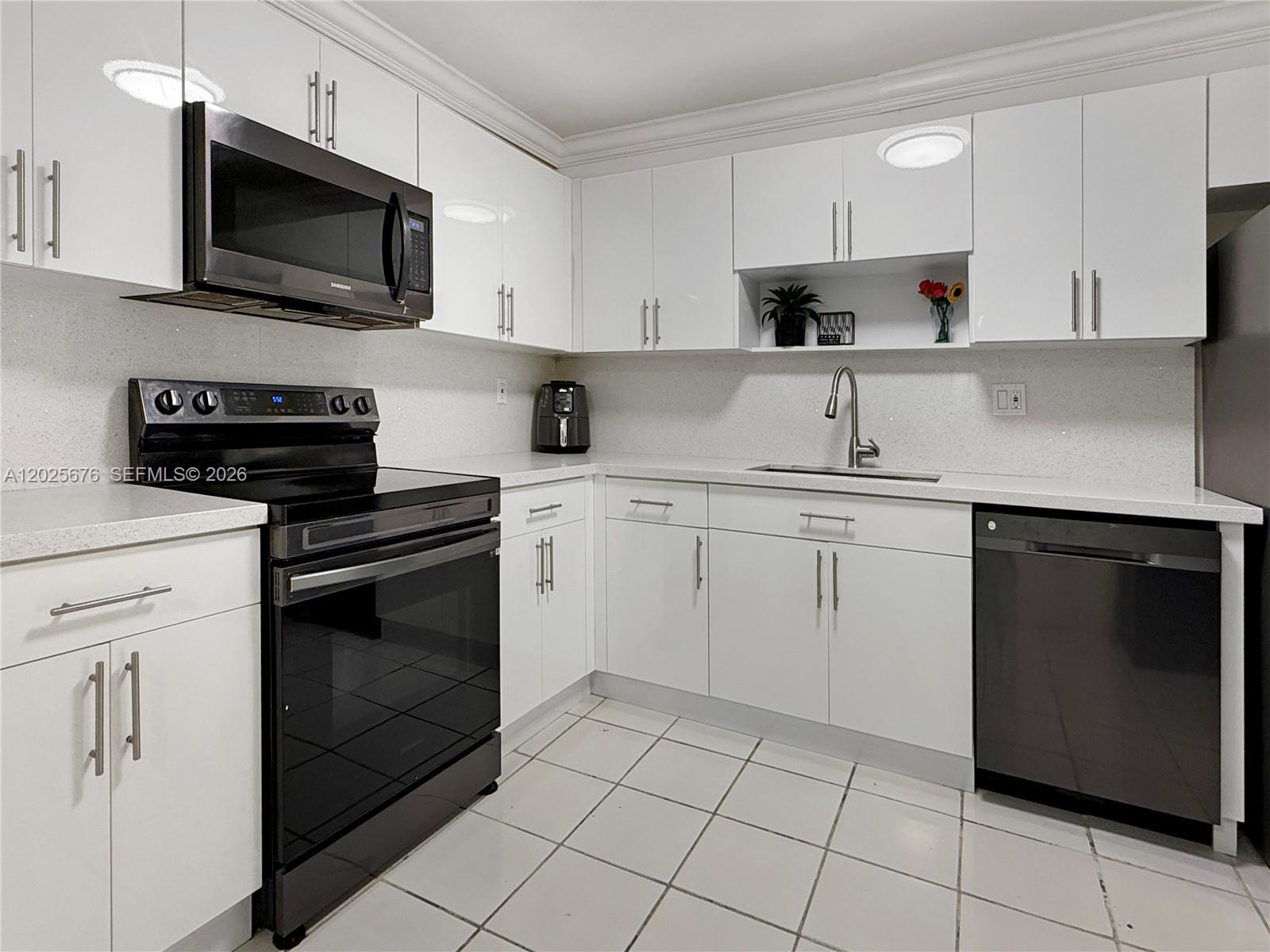 A kitchen features white cabinets, black appliances, a light countertop, and white tiled flooring — 9735 NW 52nd St # 209, Doral FL 33178, DORAL, FL