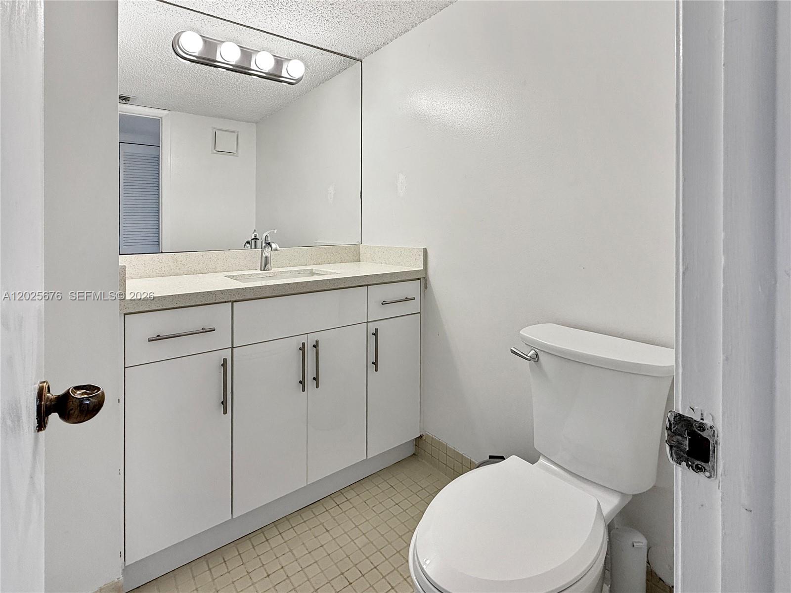 A small bathroom features a white vanity, a large mirror, and a white toilet — 9735 NW 52nd St # 209, Doral FL 33178, DORAL, FL