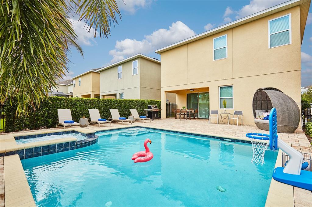 A backyard features a swimming pool with a hot tub, lounge chairs, and a basketball hoop — 351 PENDANT COURT, KISSIMMEE, FL