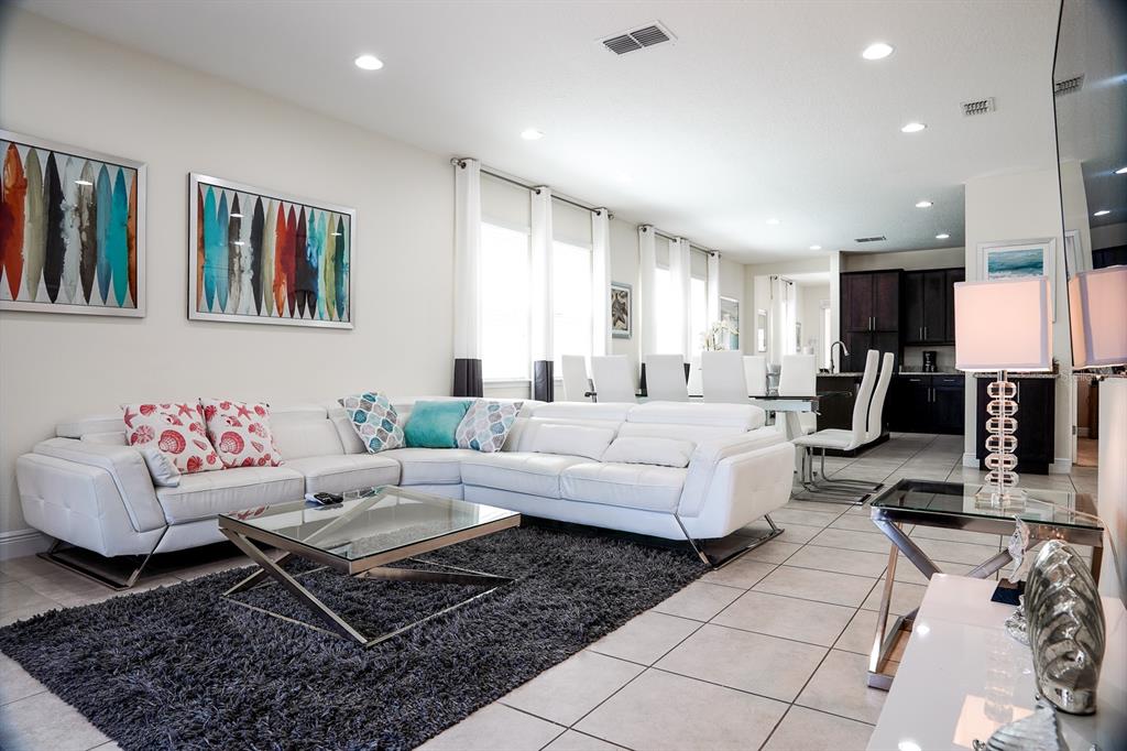 A living room with a white sectional sofa, glass coffee table, and dark area rug — 351 PENDANT COURT, KISSIMMEE, FL