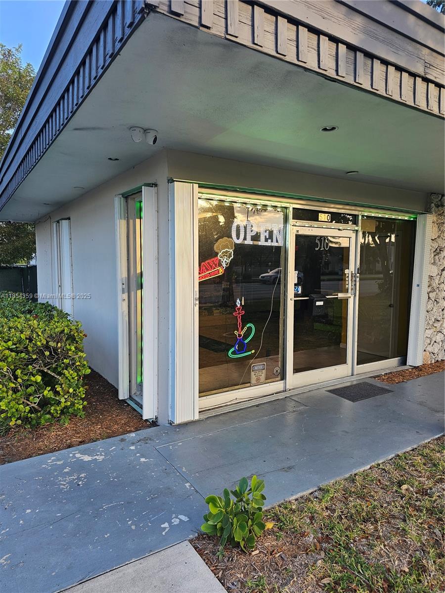 The exterior of a commercial storefront features a glass door, neon signage, and a concrete walkway — 510 s state RD 7, Plantation FL 33317, PLANTATION, FL