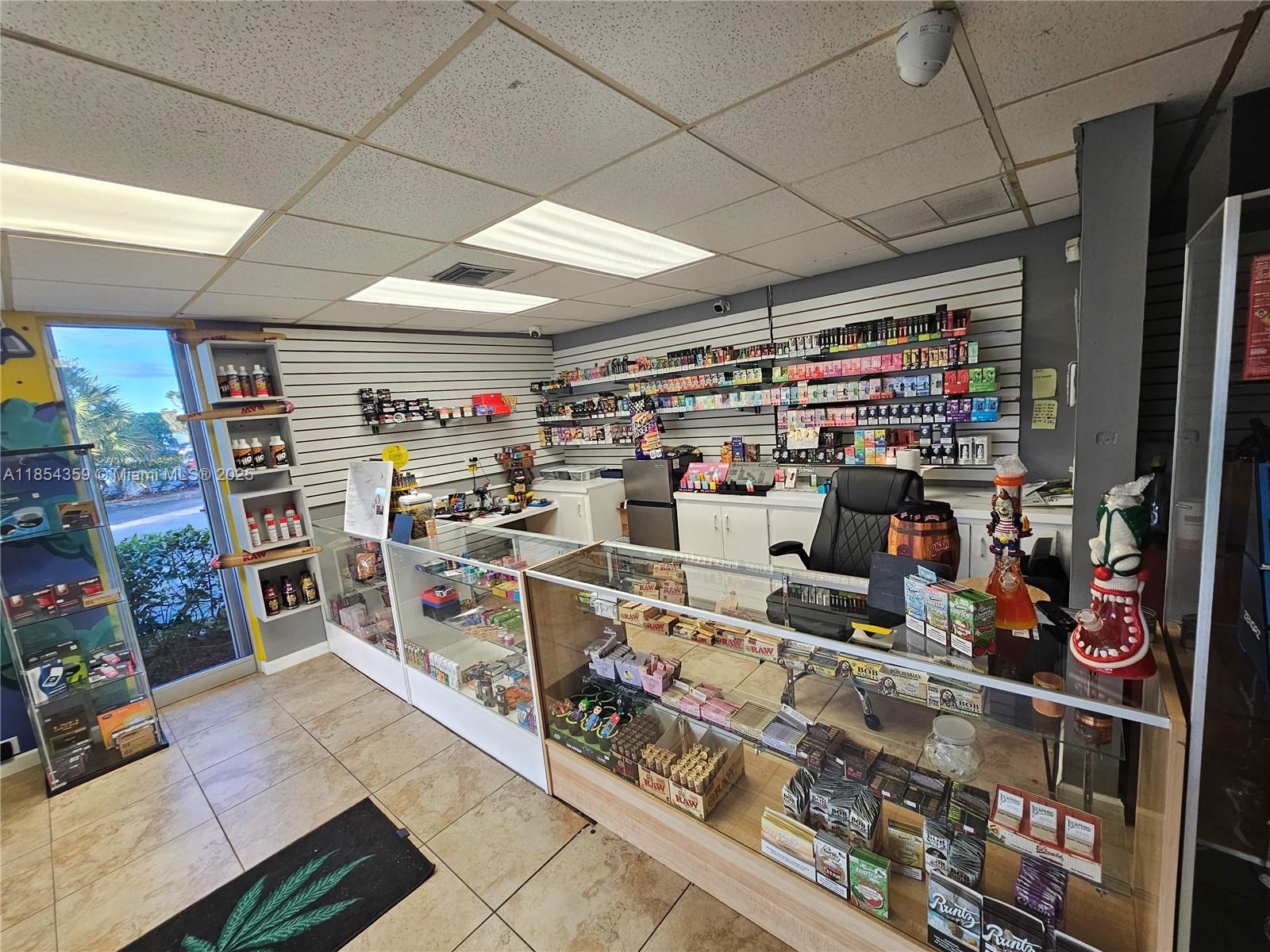 A retail smoke shop interior features glass display cases, wall-mounted shelving, and tiled flooring — 510 s state RD 7, Plantation FL 33317, PLANTATION, FL