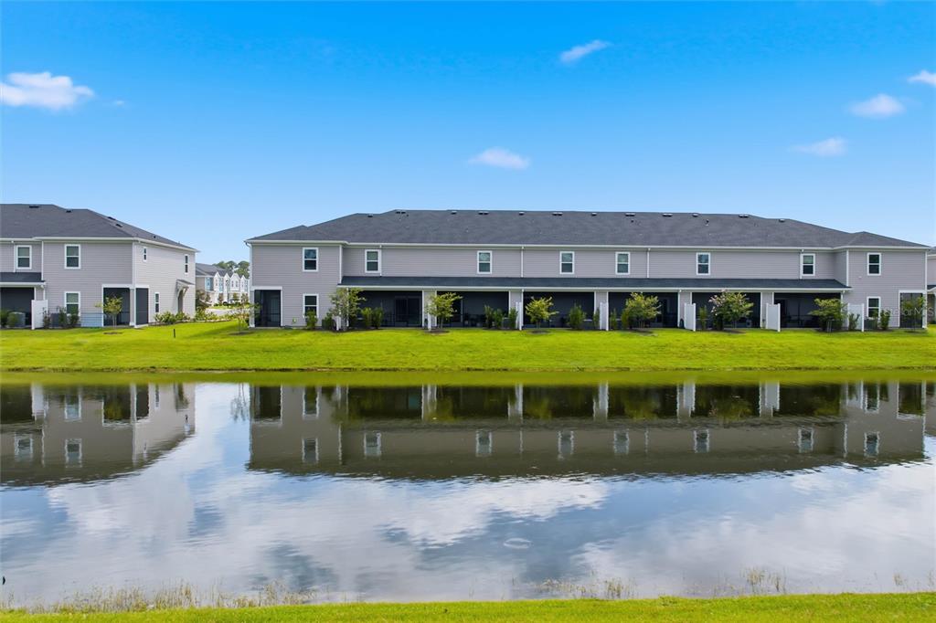 A row of two-story townhouses sits behind a pond under a clear blue sky — 6893 GABLE GROVE AVENUE, JACKSONVILLE, FL
