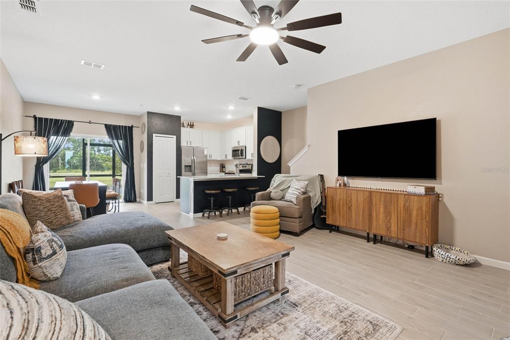 An open-concept living room features a gray sectional sofa, a wooden coffee table, and a kitchen — 6893 GABLE GROVE AVENUE, JACKSONVILLE, FL