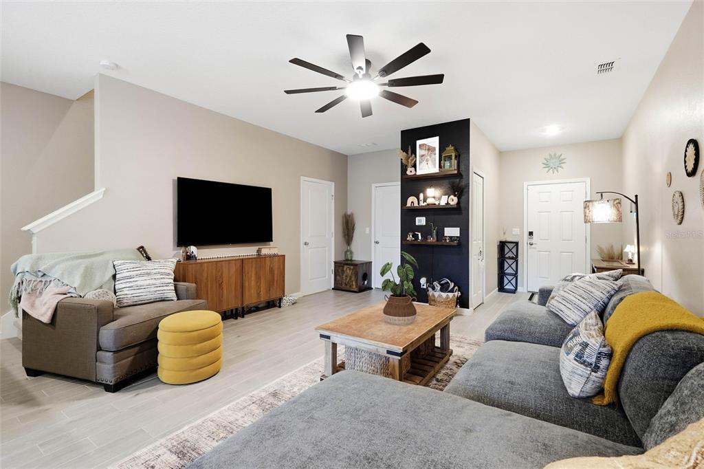 A living room features a gray sectional, a wooden coffee table, and a black accent wall — 6893 GABLE GROVE AVENUE, JACKSONVILLE, FL