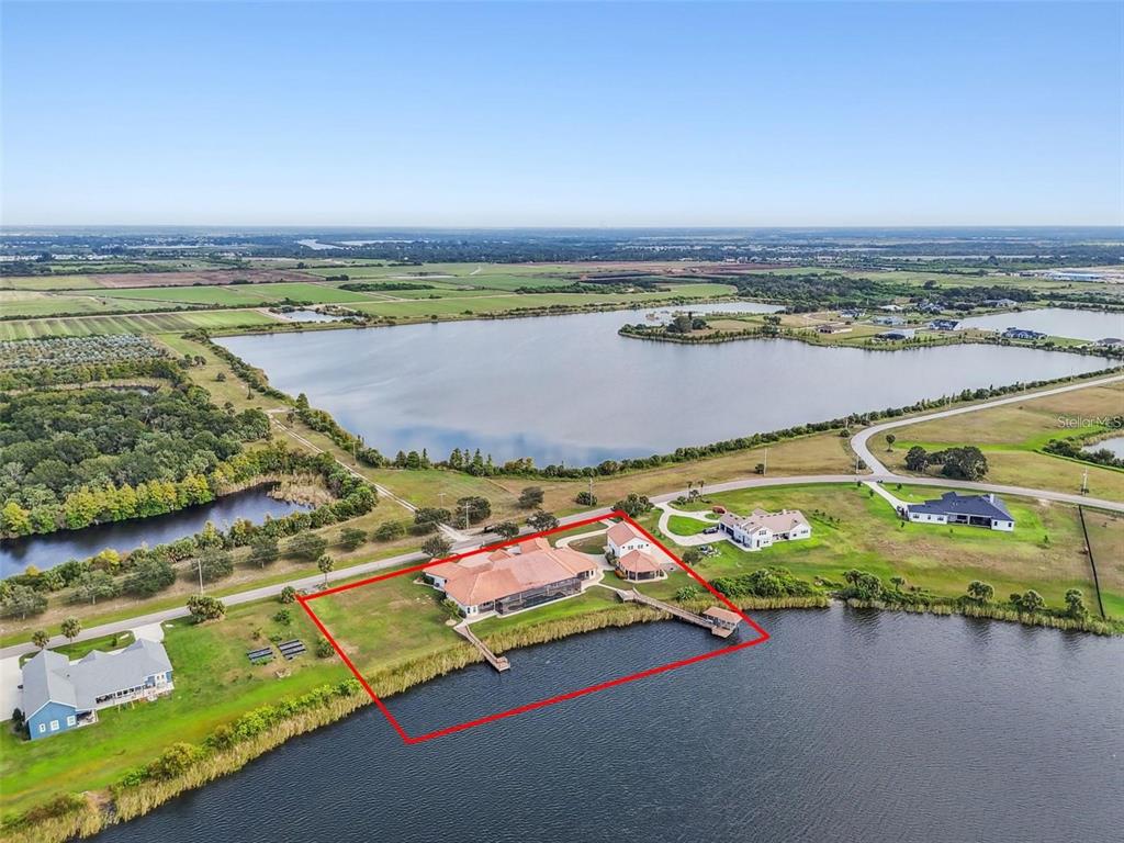 An aerial view shows a house with a red tile roof situated on a lakefront lot — 3215 GULF CITY ROAD, RUSKIN, FL