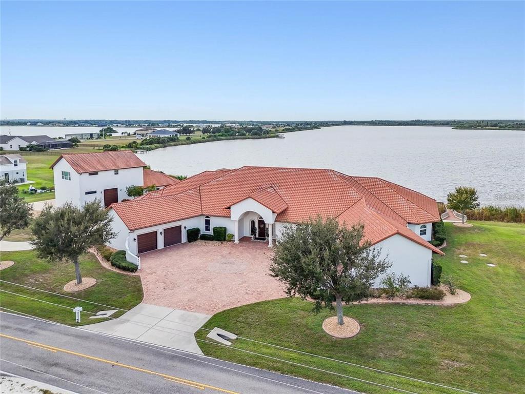 An aerial view of a white house with a red tile roof beside a lake — 3215 GULF CITY ROAD, RUSKIN, FL