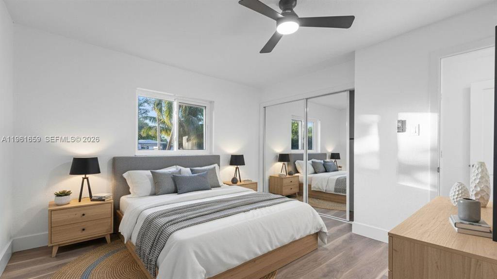 A bedroom features a bed with a gray headboard, mirrored closet doors, and wood flooring — 256 NW 78th Terrace, Margate FL 33063, MARGATE, FL