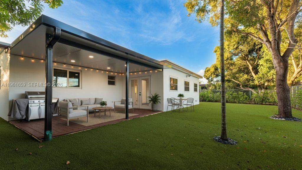 A covered patio with outdoor furniture and a grill overlooks a grassy backyard with trees — 256 NW 78th Terrace, Margate FL 33063, MARGATE, FL