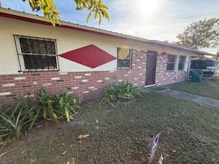 A single-story house exterior features a red diamond accent, brick siding, and barred windows — 1063 Louisiana Avenue, Clewiston FL 33440, CLEWISTON, FL