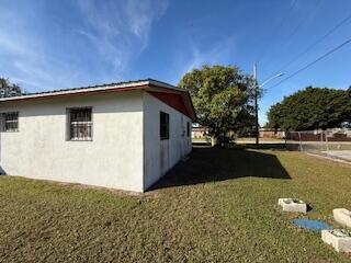The exterior of a white stucco house with a metal roof and a grassy yard — 1063 Louisiana Avenue, Clewiston FL 33440, CLEWISTON, FL