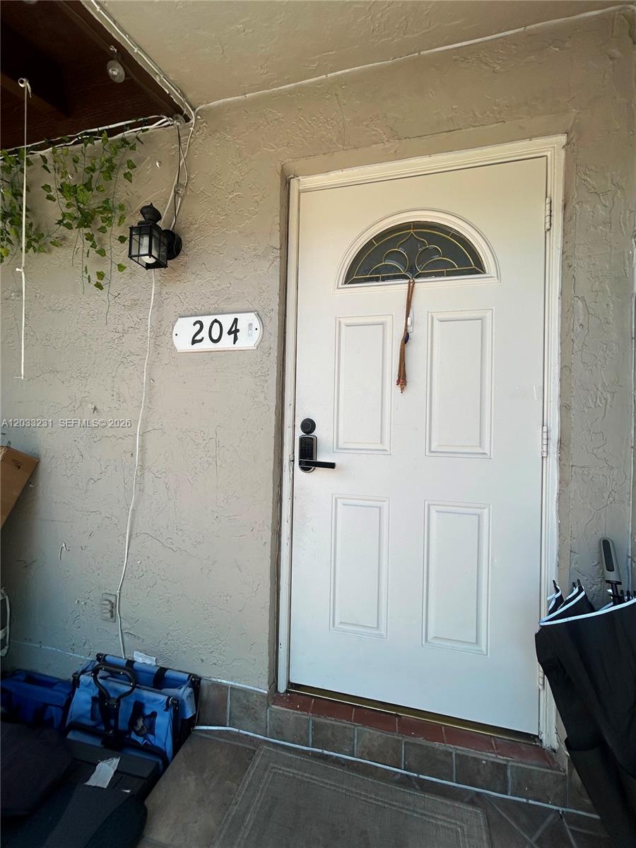 A white front door with a decorative window and a house number sign labeled 204 — 10284 NW 9th St Cir # 204, Miami FL 33172, MIAMI, FL