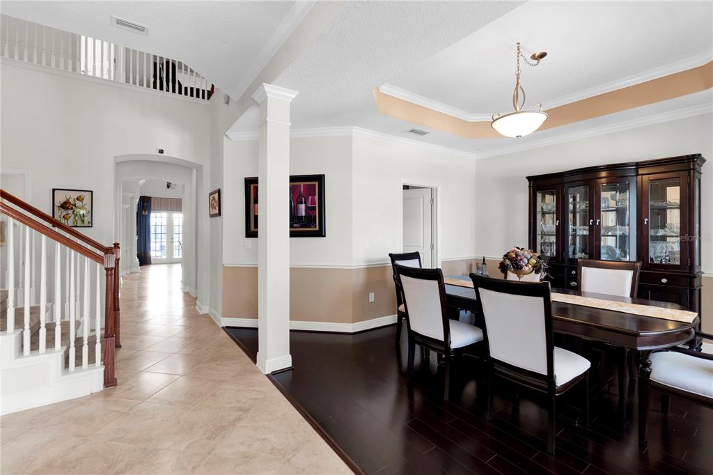 A dining room with dark wood floors and a hutch sits beside a tiled entryway — 5727 SEA TROUT PLACE, APOLLO BEACH, FL