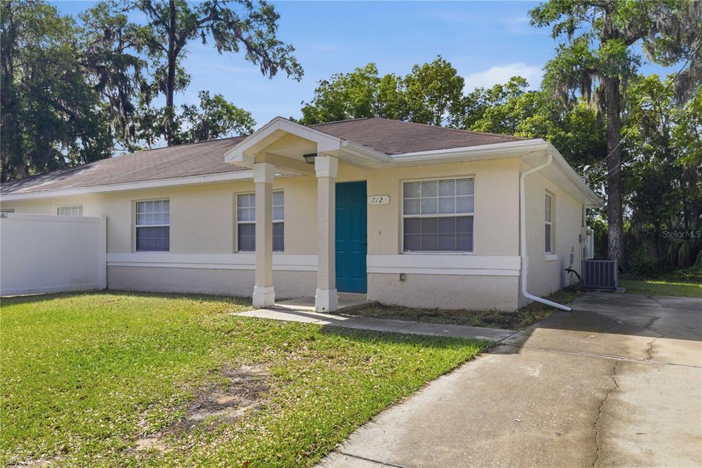 A single-story house with a teal front door, a covered porch, and a concrete driveway — 712 NE 26TH STREET, OCALA, FL