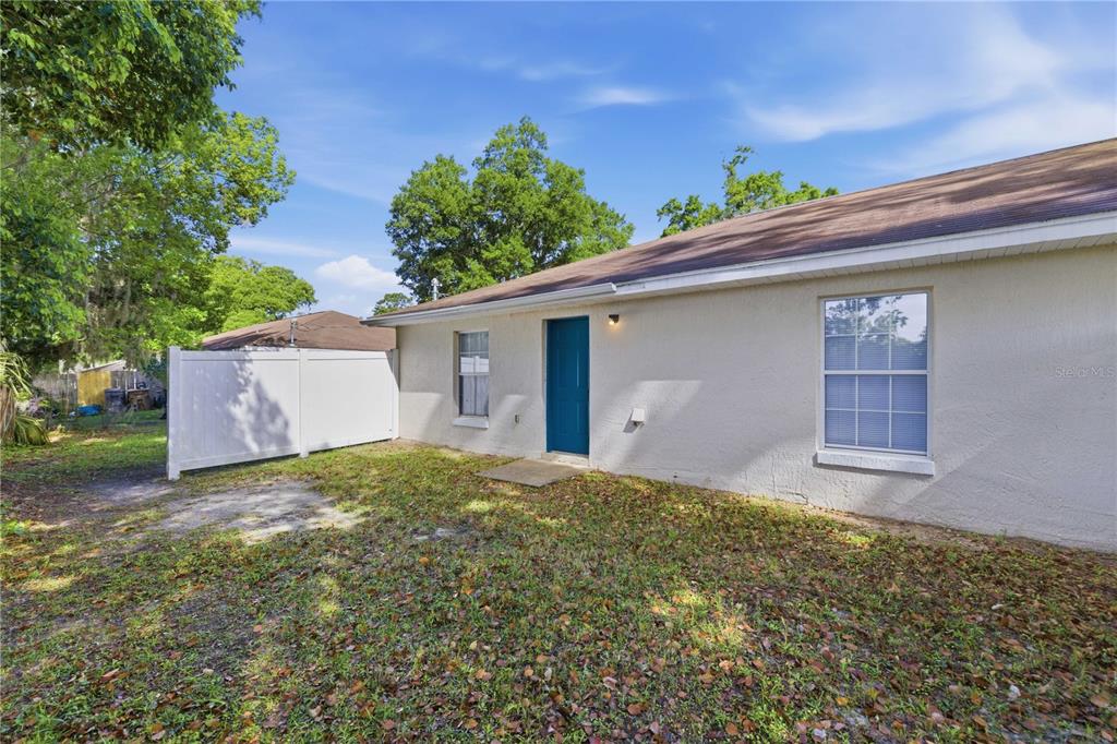 The exterior of a single-story house features a blue door, white siding, and a white fence — 712 NE 26TH STREET, OCALA, FL