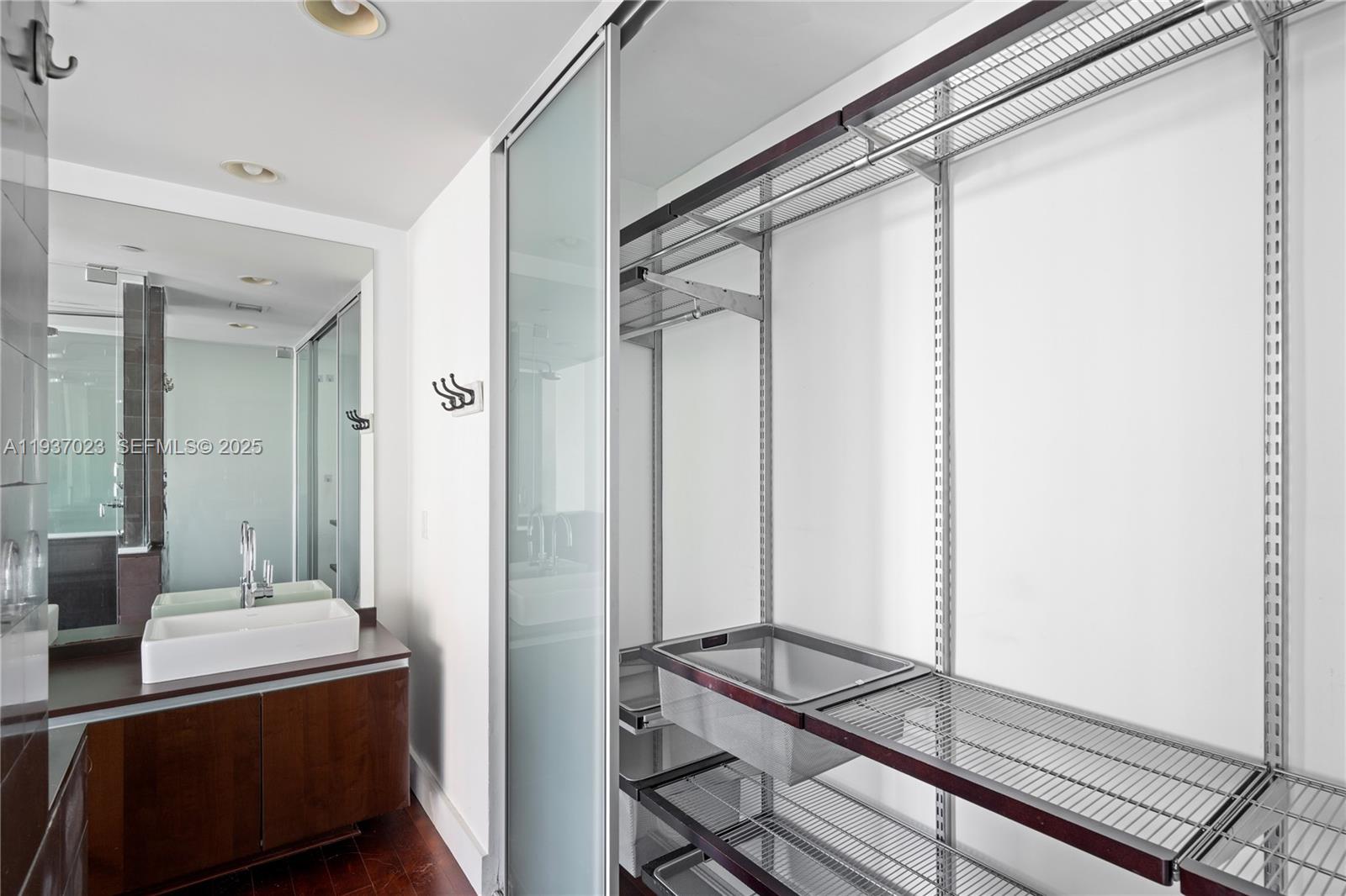 A bathroom features a wooden vanity with a white sink and an adjacent walk-in closet — 1040 Biscayne Blvd # 4108, Miami FL 33132, MIAMI, FL