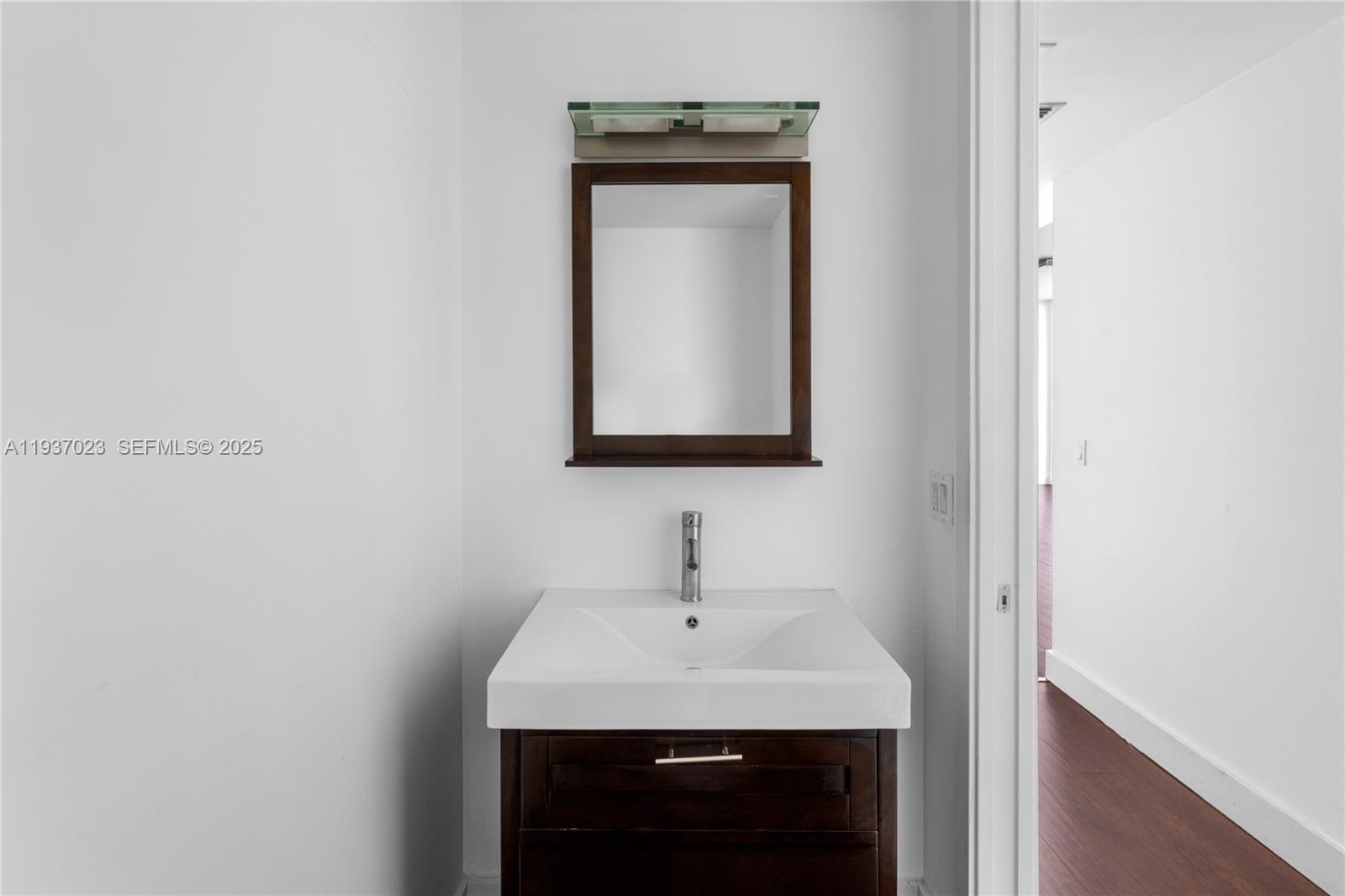 A bathroom vanity with a white sink, dark wood cabinet, and a wall-mounted mirror — 1040 Biscayne Blvd # 4108, Miami FL 33132, MIAMI, FL