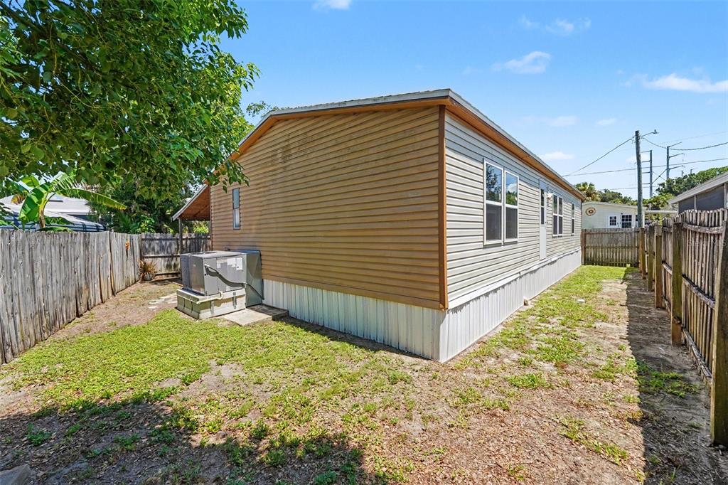 The exterior of a manufactured home features tan siding, a white skirt, and an air conditioner — 739 DRIFTWOOD LANE, TARPON SPRINGS, FL