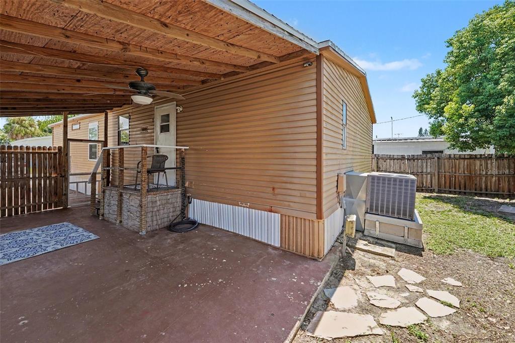 A covered patio with a concrete floor, a small porch, and an exterior air conditioning unit — 739 DRIFTWOOD LANE, TARPON SPRINGS, FL