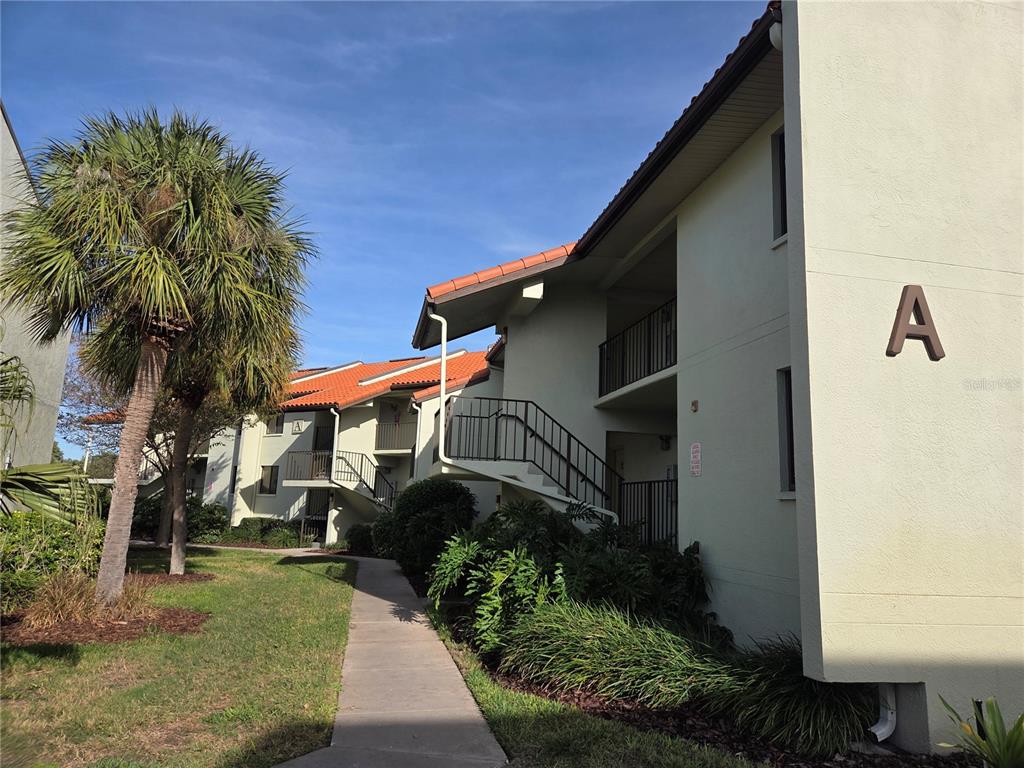 A multi-story apartment building with a walkway and palm trees under a blue sky — 1515 PINELLAS BAYWAY S UNIT A6, TIERRA VERDE, FL