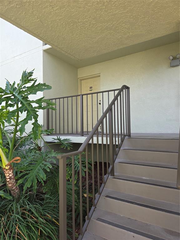 An exterior view of a staircase leading to an apartment entrance with a metal railing — 1515 PINELLAS BAYWAY S UNIT A6, TIERRA VERDE, FL