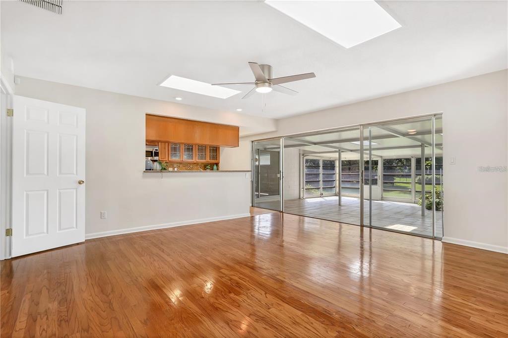 A living room with hardwood floors, a ceiling fan, and sliding doors to a lanai — 7864 BROKEN ARROW TRAIL, WINTER PARK, FL