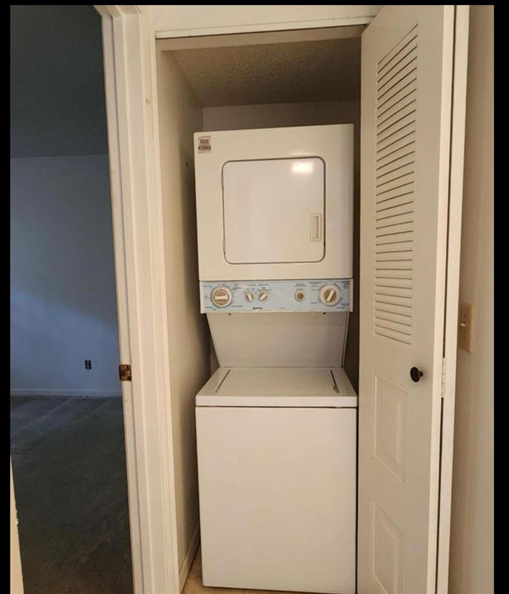 A stacked white washer and dryer unit sits inside a small laundry closet — 1698 NE Sunny Brook Lane # G206, Palm Bay FL 32905, PALM BAY, FL