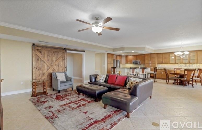 A living room features a sectional sofa, a barn door, and an open-concept kitchen — 111 E MONUMENT AVENUE UNIT 705, KISSIMMEE, FL