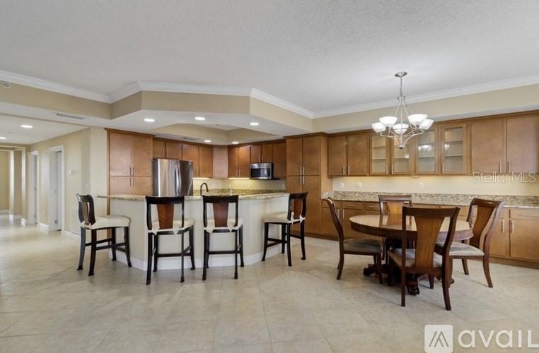A kitchen with light wood cabinets, a breakfast bar, and a dining area with chairs — 111 E MONUMENT AVENUE UNIT 705, KISSIMMEE, FL