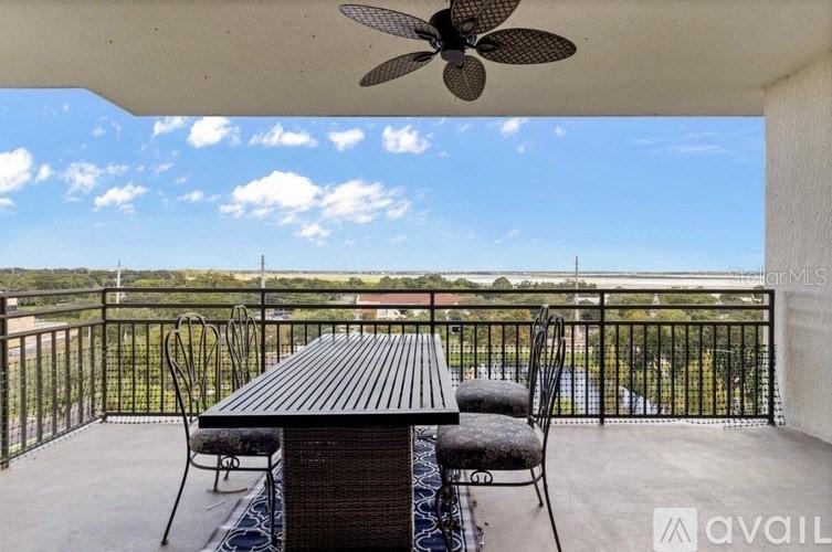 A balcony features a dining table with chairs, a ceiling fan, and a scenic outdoor view — 111 E MONUMENT AVENUE UNIT 705, KISSIMMEE, FL