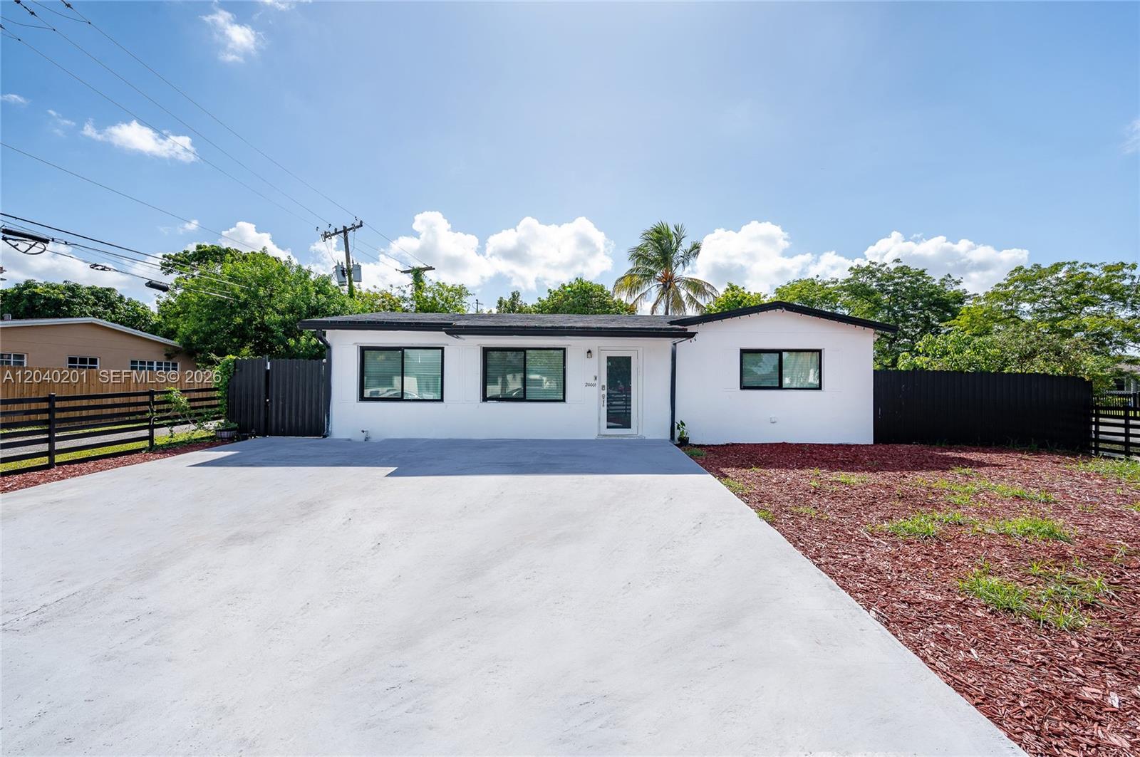 A white single-story house with a concrete driveway and black-framed windows under a blue sky — 20001 NW 14th Ave, Miami Gardens FL 33169, MIAMI GARDENS, FL