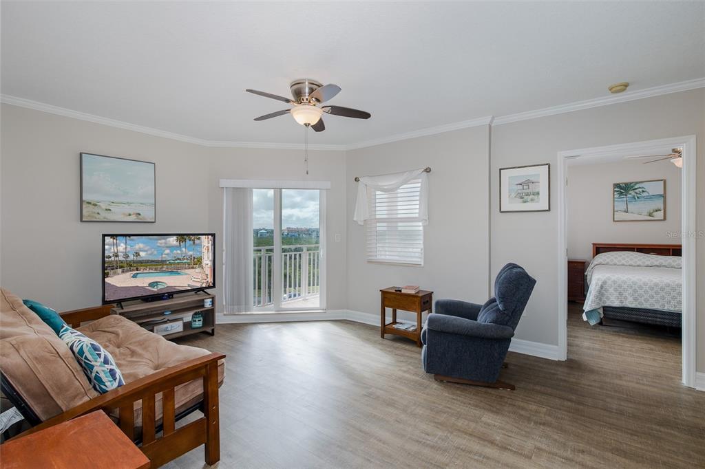 A living room with wood-look flooring, a ceiling fan, a television, and a balcony view — 4516 SEAGULL DRIVE UNIT 411, NEW PORT RICHEY, FL