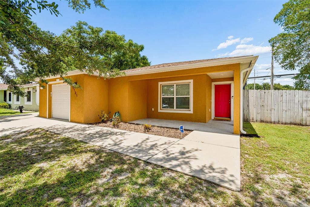 A single-story house with yellow stucco walls, a red front door, and a concrete driveway — 5101 LANETTE STREET, ORLANDO, FL