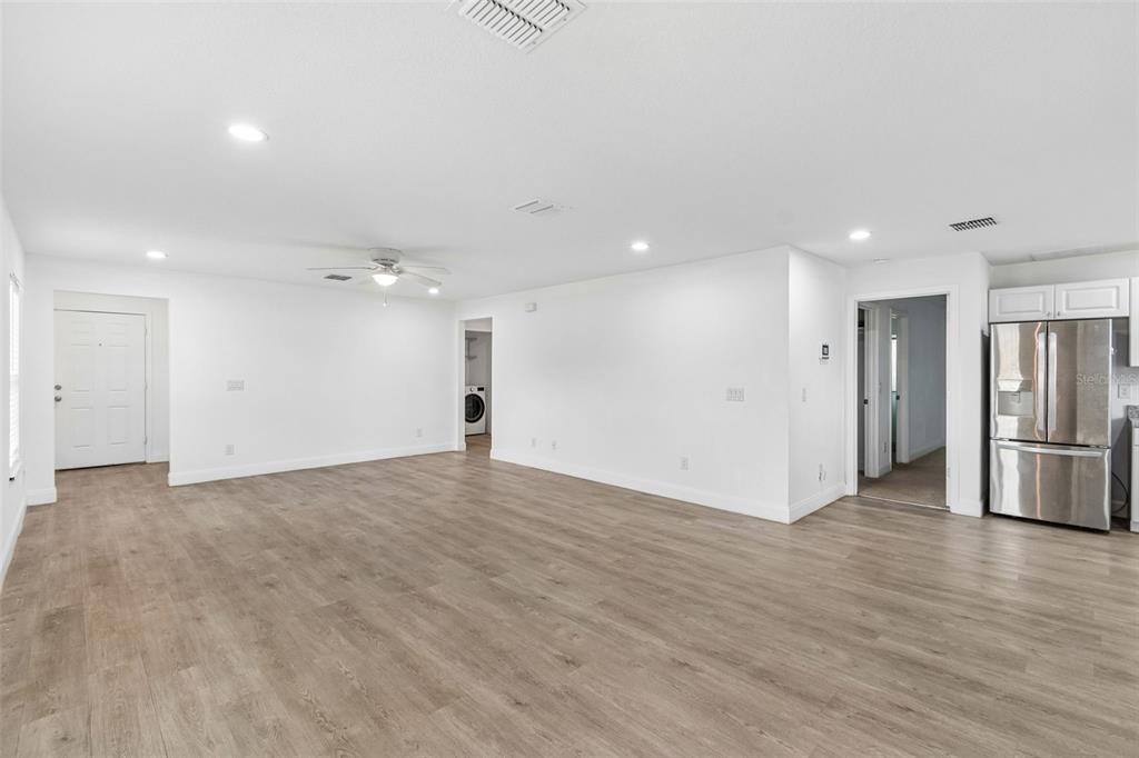 An open-concept living area features light wood-look flooring, white walls, recessed lighting, and a refrigerator — 5101 LANETTE STREET, ORLANDO, FL