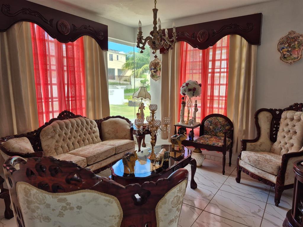 A living room features ornate wooden furniture, tufted sofas, a chandelier, and large windows — Carr. 414, Km. 3.5 BO. CRUCES, RINCON, PR