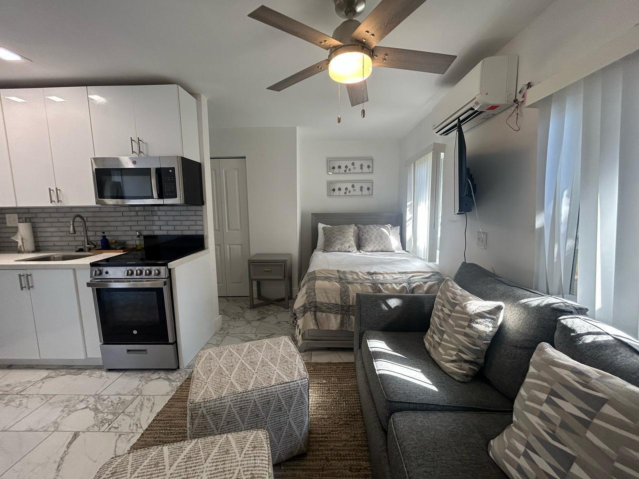 A studio apartment features a kitchen with white cabinets, a bed, and a gray sofa — 201 S Ocean Boulevard # 7, Boca Raton FL 33432, BOCA RATON, FL
