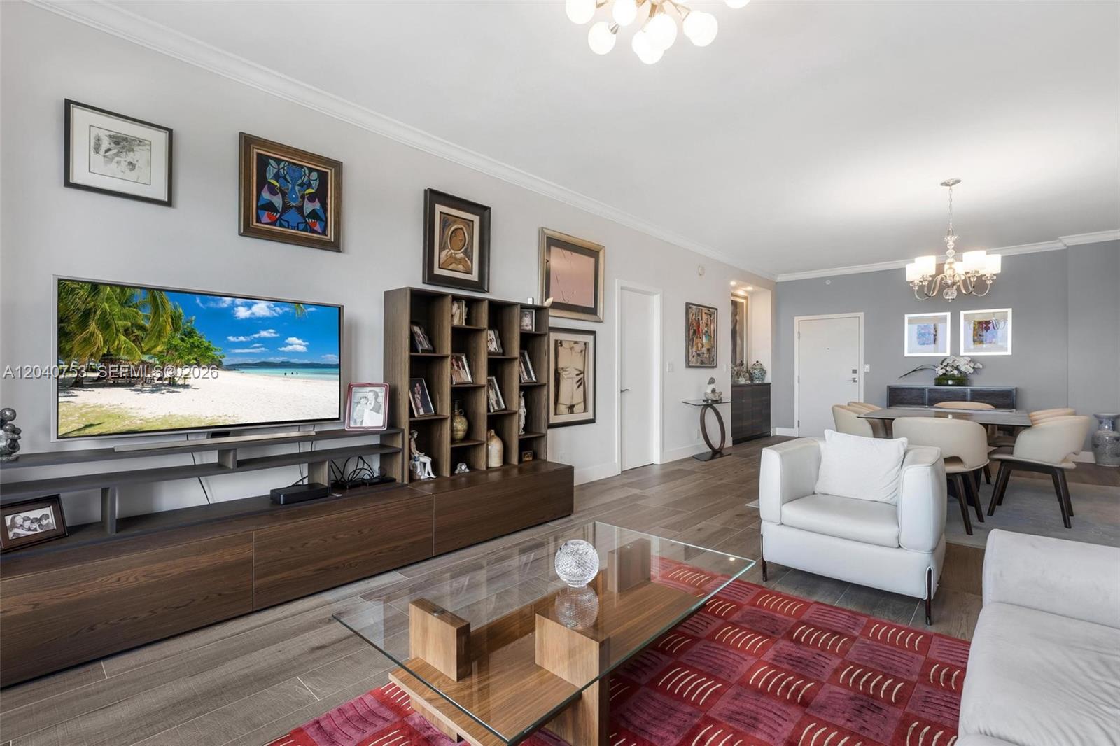 A living room features a television, wooden shelving, a glass coffee table, and dining area — 90 Edgewater Dr, Coral Gables FL 33133, CORAL GABLES, FL